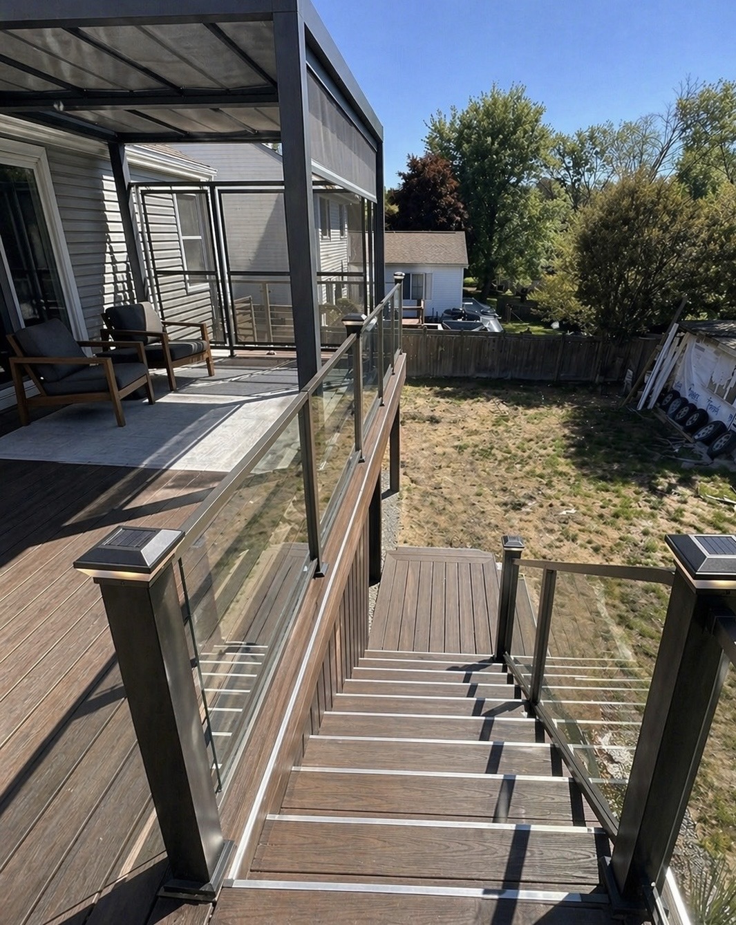 Custom Trex composite deck in Loudoun County VA with glass railings, pergola, and solar post lights